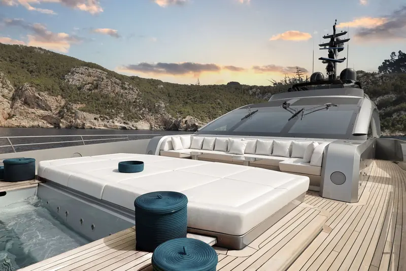 The sundeck jacuzzi and day bed tucked against a wooded cove, the pilothouse glazing behind still showing the last of the light.