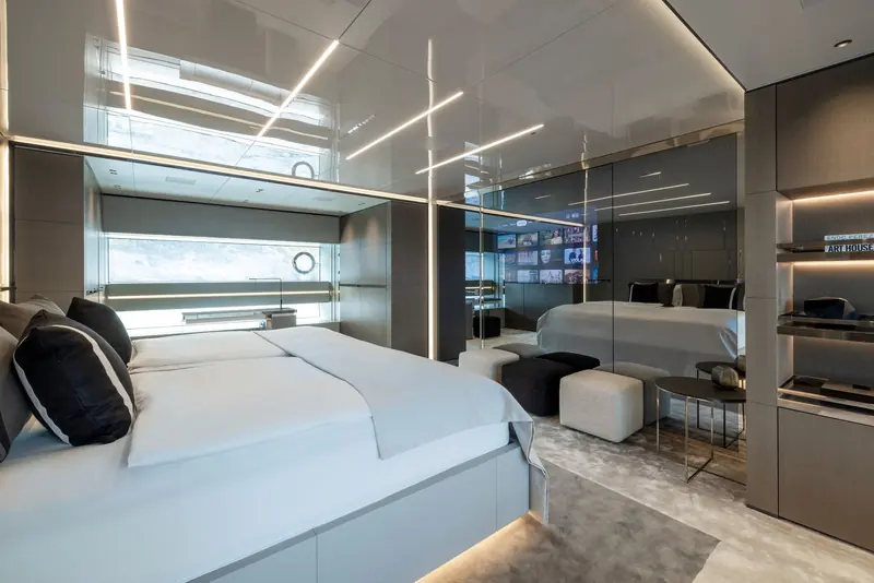 A guest suite with a mirrored partition to a hidden dressing area and a fold-out video wall in place of conventional art.