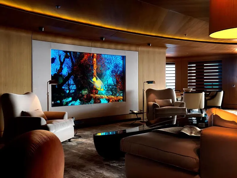 The cinema room, with a full-wall screen and deep reclining seating in a separate compartment from the main salon rather than a fold-down screen sharing the lounge.