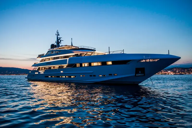 At anchor off the Cote d'Azur, her dark blue hull holding the last colour of the sky in a near-flat sea.