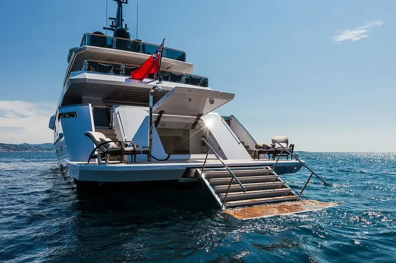 The stern platform lowered to the waterline, teak steps and deck loungers set out for a swim stop.