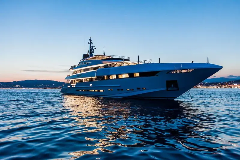 Bow-on into the evening light, the raked stem and stacked decks showing the full scale of a 68-metre custom build.