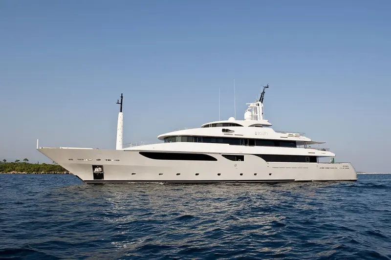 At a slower cruise off the coast, the full broadside view shows three continuous decks of glazing running the length of the superstructure.