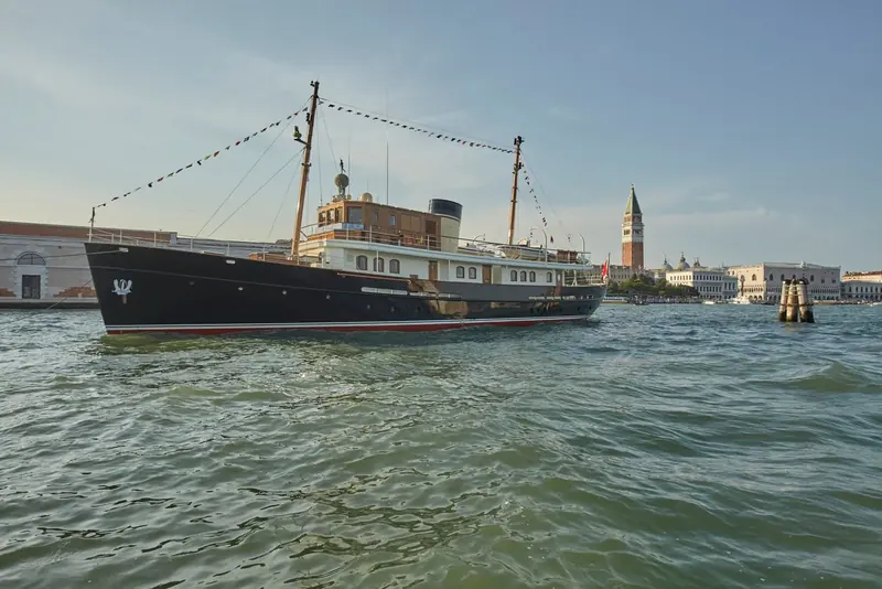 Taransay passing St Mark's Campanile and the Doge's Palace, her 1930s-style black hull and varnished masts unmistakable against Venice.