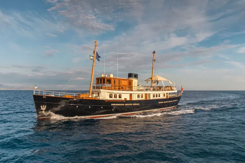 Underway off an Italian coastline, the counter stern and single tall funnel giving away her classic steam-yacht profile.