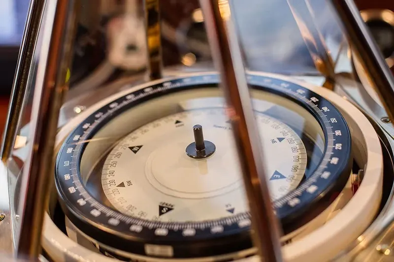 A close-up of the ship's compass, its brass gimbal and hand-painted card kept as functioning instruments, not decoration.