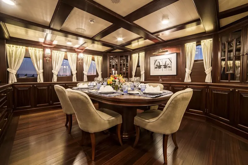 The formal dining room panelled floor to ceiling in dark wood, curtained windows and a table set for six.