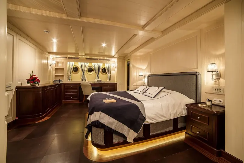 A guest cabin with portholes dressed in fabric curtains rather than blinds, keeping the period detailing below decks too.