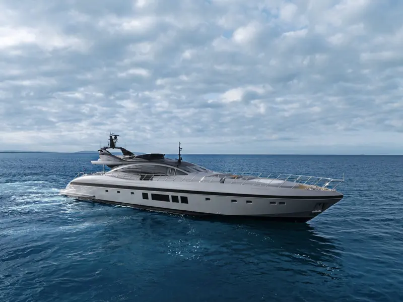 The 132E against a hazy coastal backdrop, foredeck sunpad and low windscreen visible from the beam.