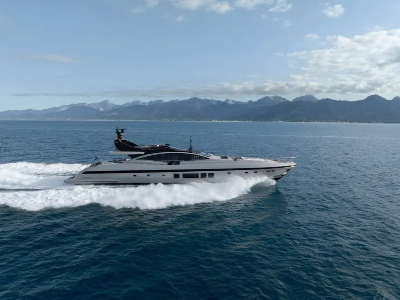 Running shot against mountainous coastline, the flybridge-free low-profile deckhouse that defines Mangusta's open-yacht silhouette.