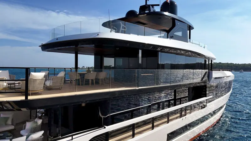 Flybridge seating and sunpads viewed from the bow, with the wraparound glass balustrade that gives the upper deck its open, unbroken sightline to the water.