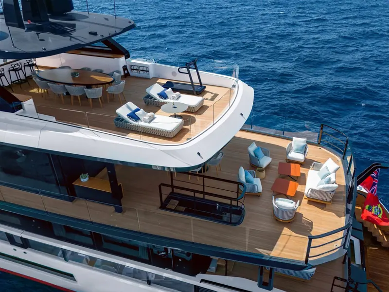 Upper deck dining and lounge area, teak underfoot, with the helm console visible forward under its own hardtop.