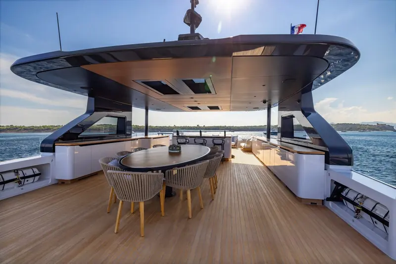 Aft cockpit dining table shaded by the flybridge overhang - a sail-shaped hardtop rather than a flat roof, a detail carried across the Oceano line.