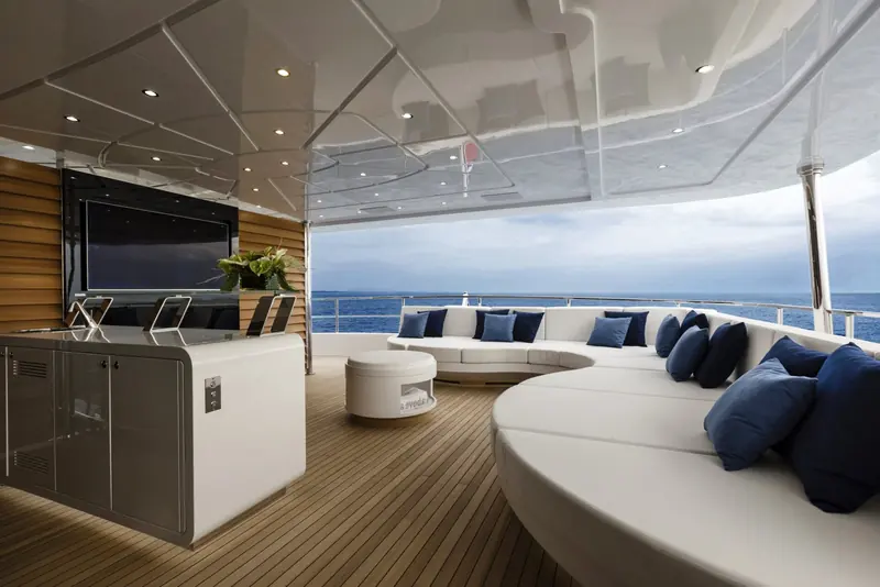 Aft deck galley and lounge under the flybridge overhang, with teak decking and an outdoor kitchen for al fresco dining underway.