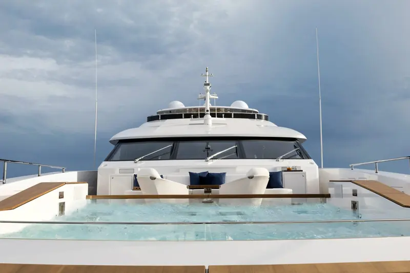 The forward jacuzzi under a darkening sky, glass wind-break panels keeping the pool usable at speed.
