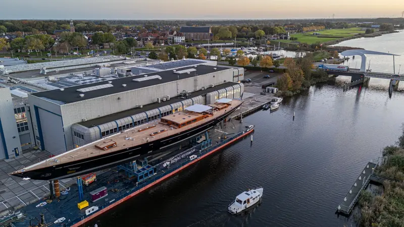 Aquarius in the basin at Royal Huisman's Vollenhove yard shortly before launch, the black hull still dockside among the yard's build sheds.