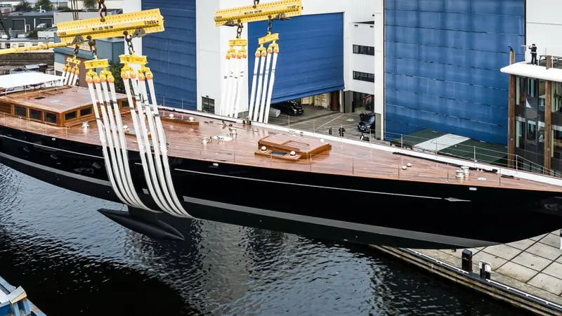 Mast-stepping at the yard: Aquarius's rig lowered into place by crane, the four-spreader mast and standing rigging laid out on deck ready for tensioning.