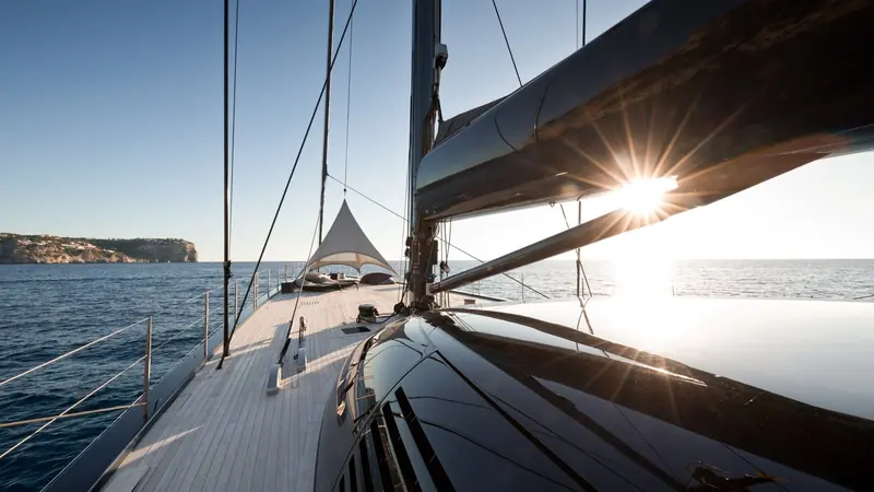 Sun flaring straight through the mainsail on a close reach, the trim and shape of a rig built to be sailed properly, not just displayed.
