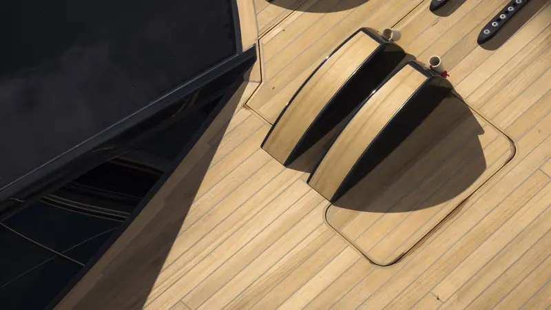The recessed housing in the teak foredeck for the retractable drive leg, the fitting that lets Sarissa motor out of an anchorage with nothing hanging in the water to slow her under sail.