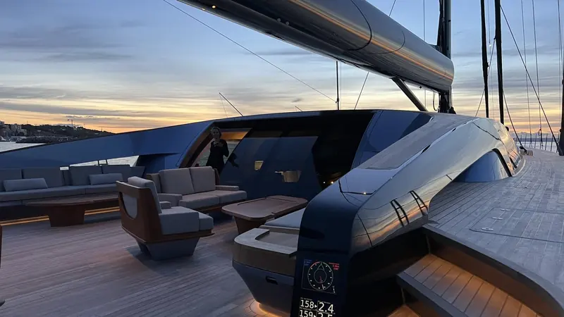 The aft deck lounge at dusk in port, a crew member aboard and the cockpit repeater showing heading and speed, the everyday view from the helm rather than a staged shot.