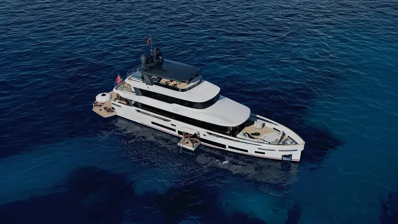 Sirena 118 at anchor off a wooded Turkish headland, the flybridge Jacuzzi and forward sunpad both laid out for guests before a single line is cast off.
