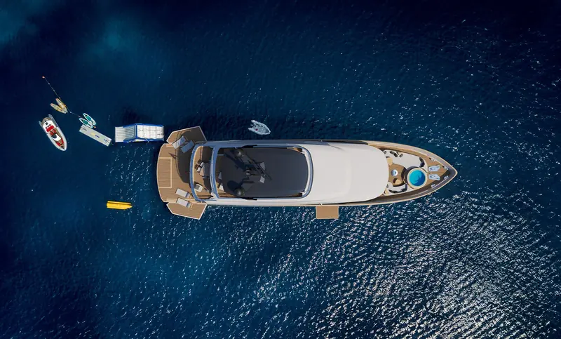 Straight overhead at anchor with the full toy spread deployed: jet ski, paddleboards, an inflatable mat, a chase tender and a small yellow submersible scooter.