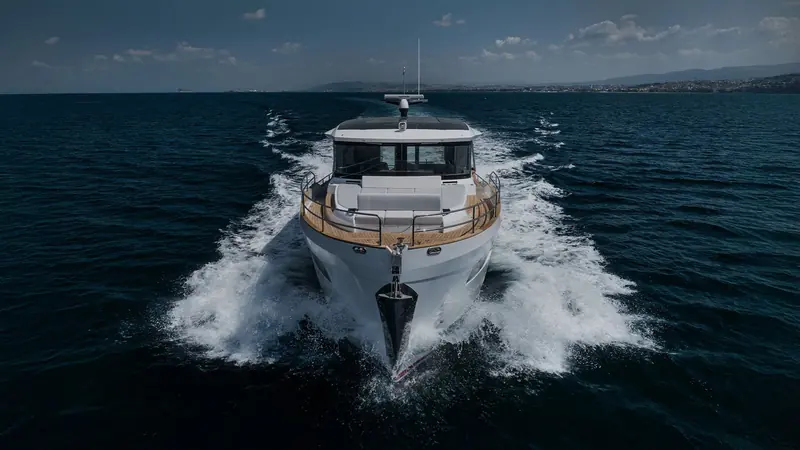 Running bow-on against a hard chine and full-width aft bench seating, the wake showing a genuine planing hull rather than a semi-displacement one.
