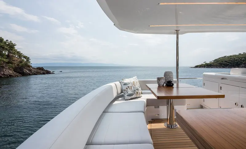 An aft cockpit sofa built into the transom bulwark, angled to face a dining table rather than out to the wake.