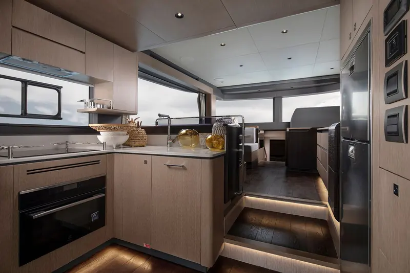 The galley runs fore-and-aft down one side rather than across the beam, freeing a full-width dinette opposite it.