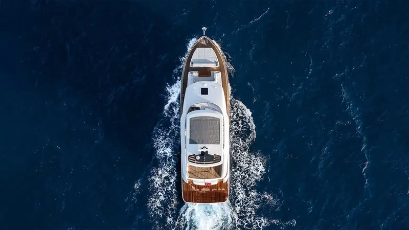 Straight overhead, the Sirena 60's varnished teak transom and Turkish courtesy flag show through the spray of her own wake.