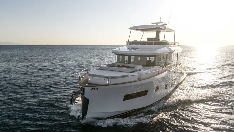 Running into low sun, the hard bimini over the flybridge throws a long shadow across the teak-laid deck below it.