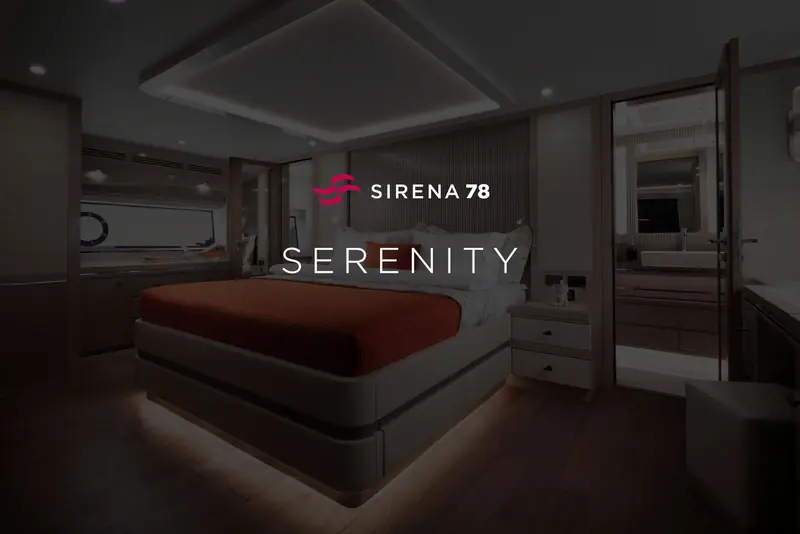 The owner's cabin aboard Serenity, named on the bulkhead plaque: a full-beam berth in warm oak with a private ensuite through the sliding door aft.