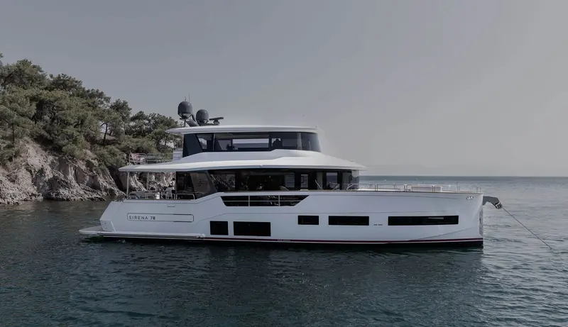 Coasting past a wooded shoreline, the low sheer line and dark hull windows that carry through the whole Sirena range.