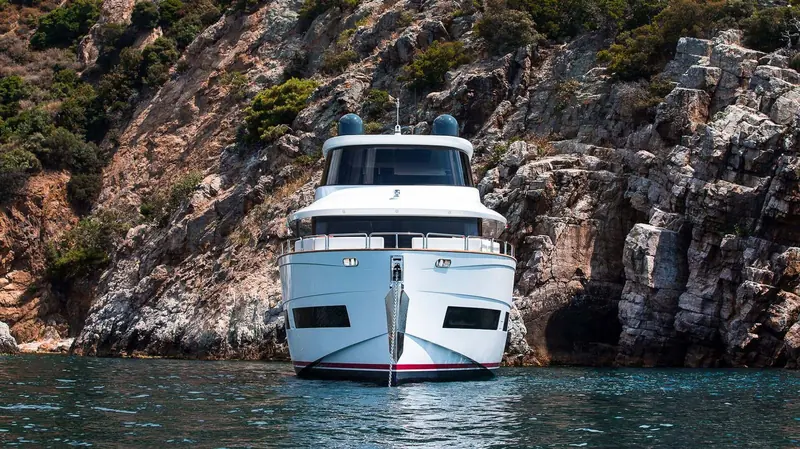 Tucked bow-in against a limestone cove wall, showing how close inshore the boat can sit at anchor.