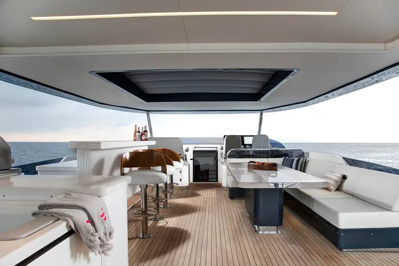 The flybridge bar and aft lounge, stocked bottles and a folded towel left out as if a charter guest had just stepped away.