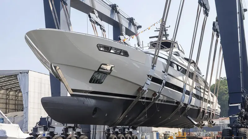 Slung from the yard's travel lift on launch day, showing the propellers, shafts and running gear normally hidden underwater.