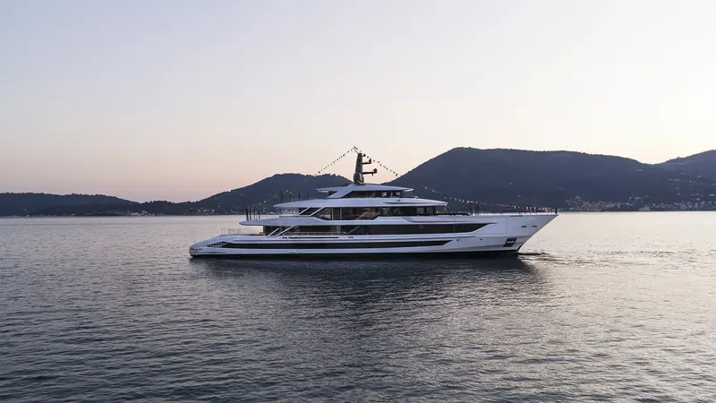 The first Baglietto T60 dressed in signal flags at her handover, anchored off the Ligurian coast at dusk after the yard confirmed she had already found a second buyer for hull number two.