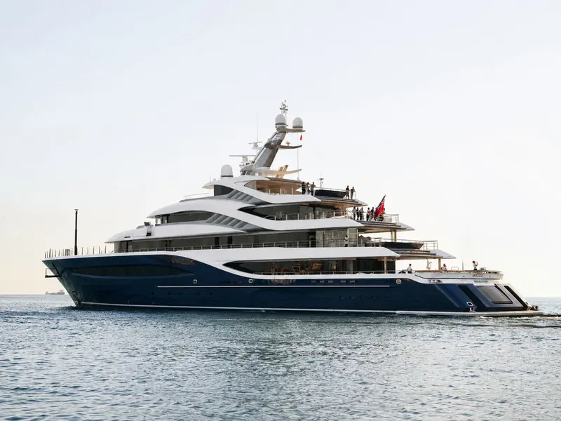 Guests and crew on Angelique's upper decks as she gets underway, her wake stretching astern.