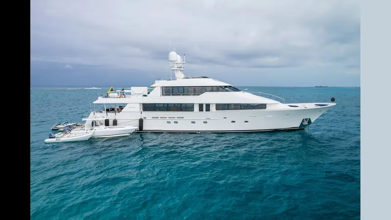 Avalina, the 2003 hull, anchored over a reef flat with a RIB and a second tender rafted alongside and a pair of jet skis parked on the swim step.