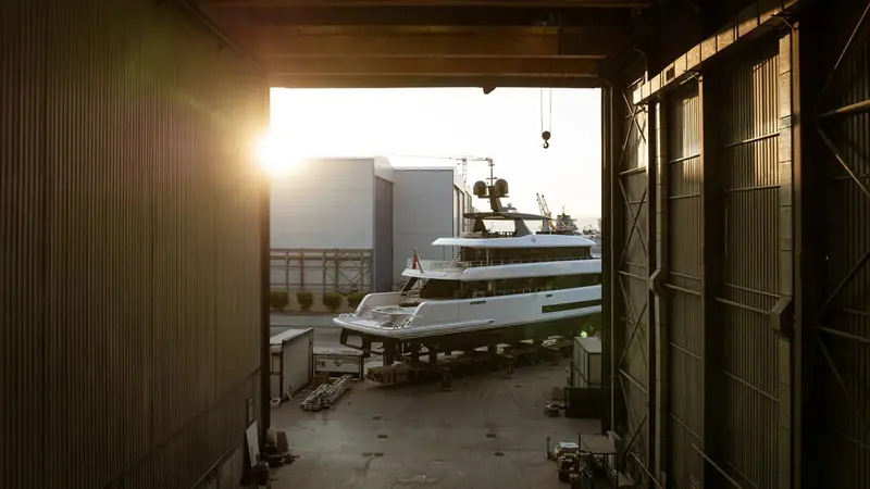 Backlit by the evening sun, the 42M is towed clear of the construction hall on its self-propelled modular transporter, crane hook still overhead.