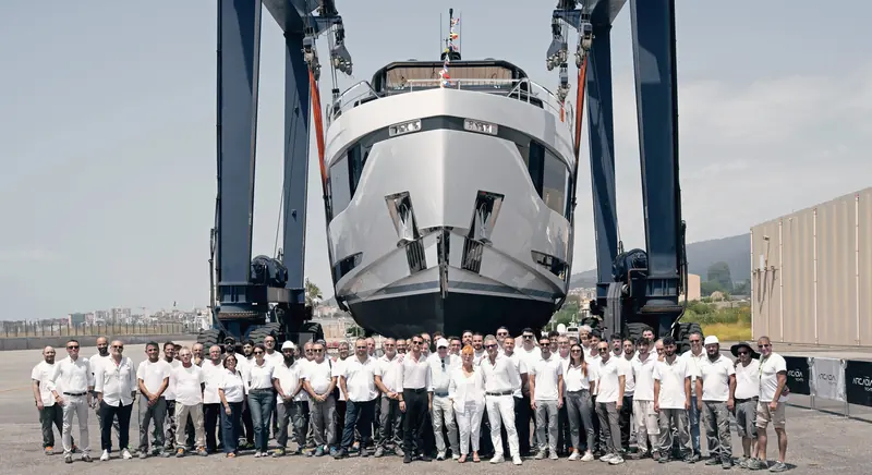 The third Arcadia A80 hull, bow-on in the travel lift with shipyard staff, at launch in the last days of July 2026.