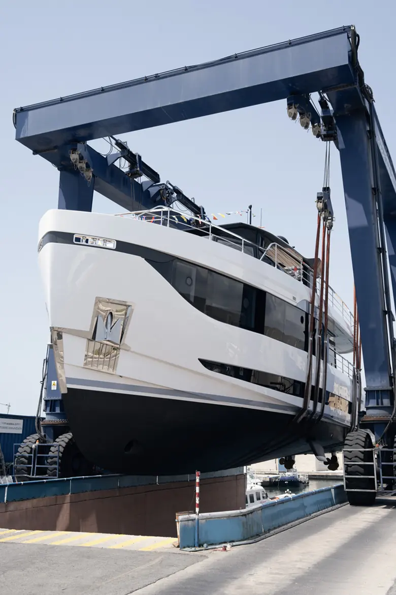 The same hull suspended in the travel lift moments before entering the water.