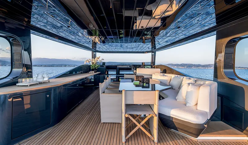 The covered aft-deck dining and lounge area aboard an Arcadia A80, underway along the coast.