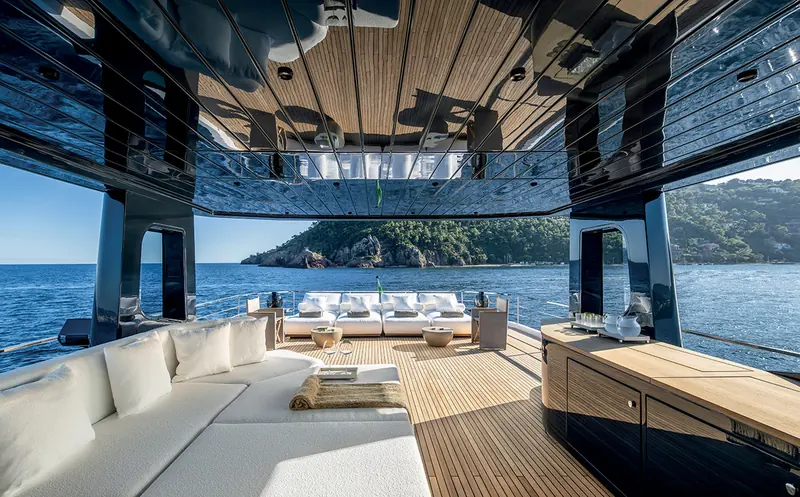 The upper sun deck lounge of an Arcadia A80, anchored off a rocky coastline.
