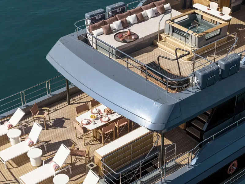 A jacuzzi, sun pads and a shaded dining table share the sun deck, the kind of separate upper-deck living space that comes with the 102's extra beam.