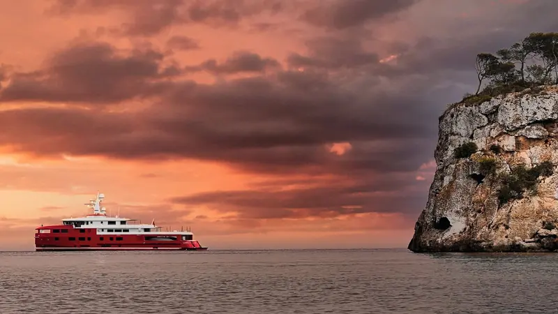 Akula underway under a red and orange sunset sky.
