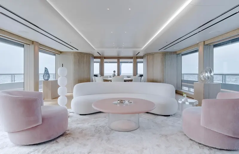 The main saloon aboard Entourage, with Burdifilek's curved boucle sofa and pink velvet swivel chairs around an organic-shaped coffee table.