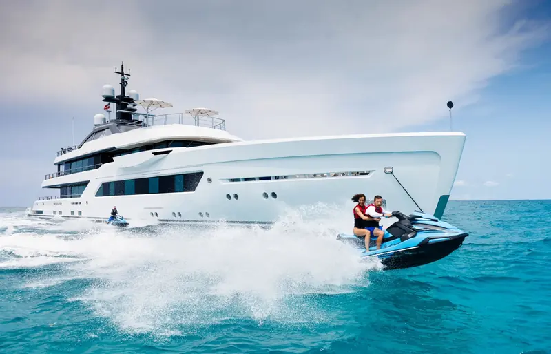 Entourage under way bow-on, with guests riding a personal watercraft alongside off her stern.