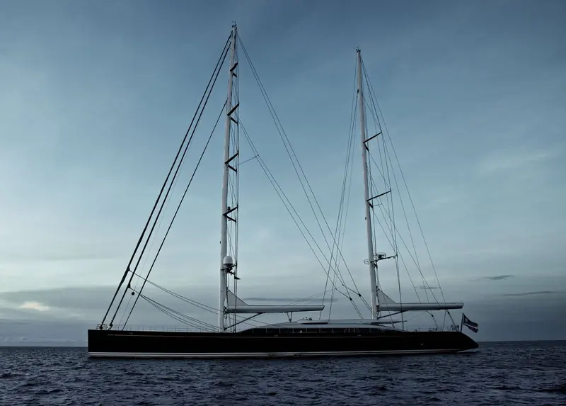 Vertigo, the 67.2 metre Alloy Yachts ketch with a Liaigre interior, lies at anchor at dusk under her twin masts.