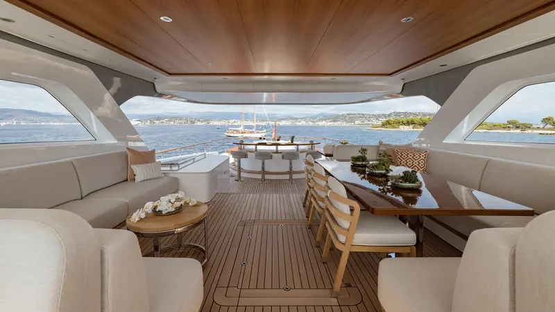 Solemates' aft deck lounge and dining table open to the sea, a classic schooner passing astern.